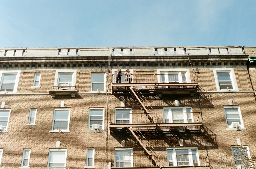 First-time buyers looking up at a UK block of leasehold flats before a viewing