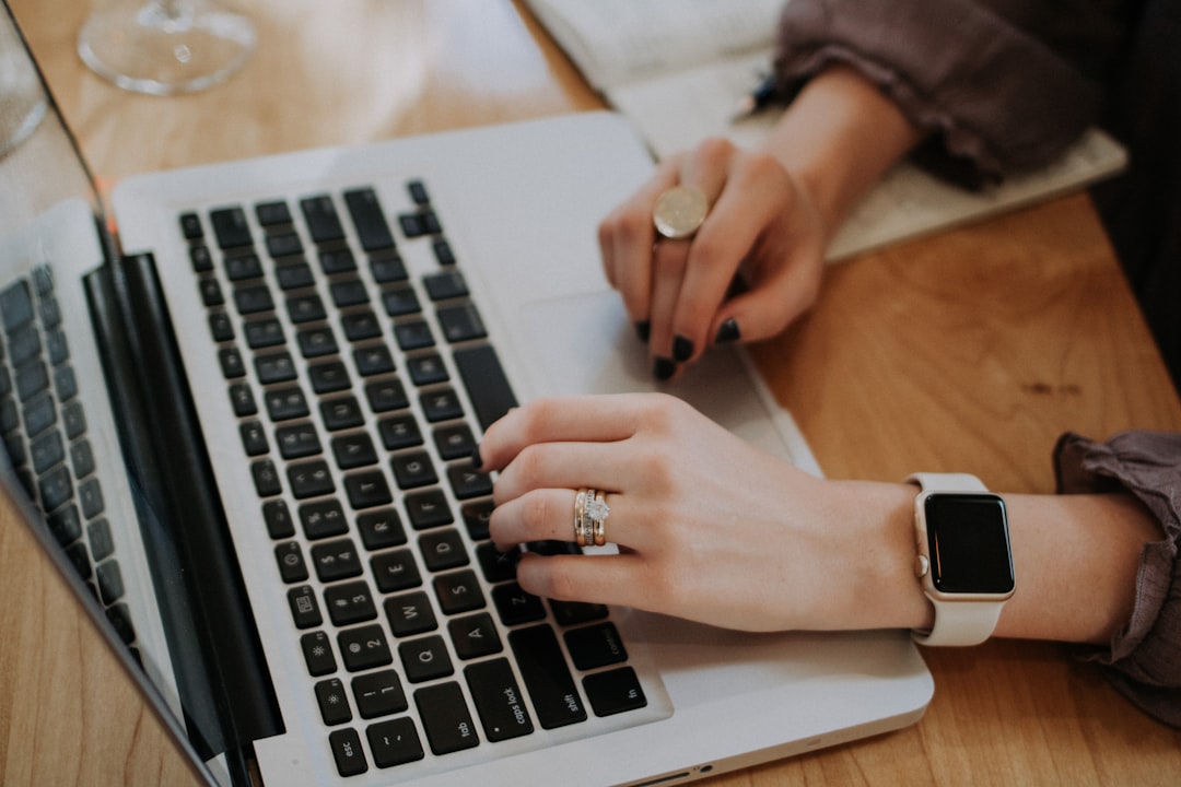 A buyer at a kitchen table writing notes beside a laptop while preparing ChatGPT prompts for buying a house