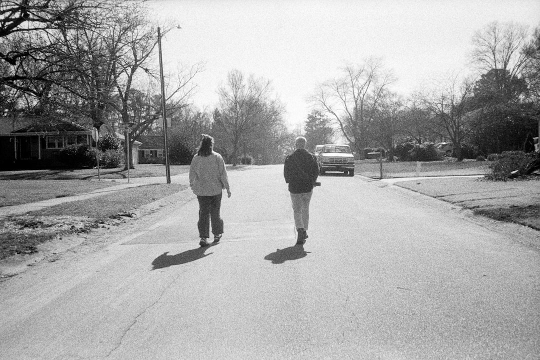 A couple walking through a UK residential street while researching areas to buy a house